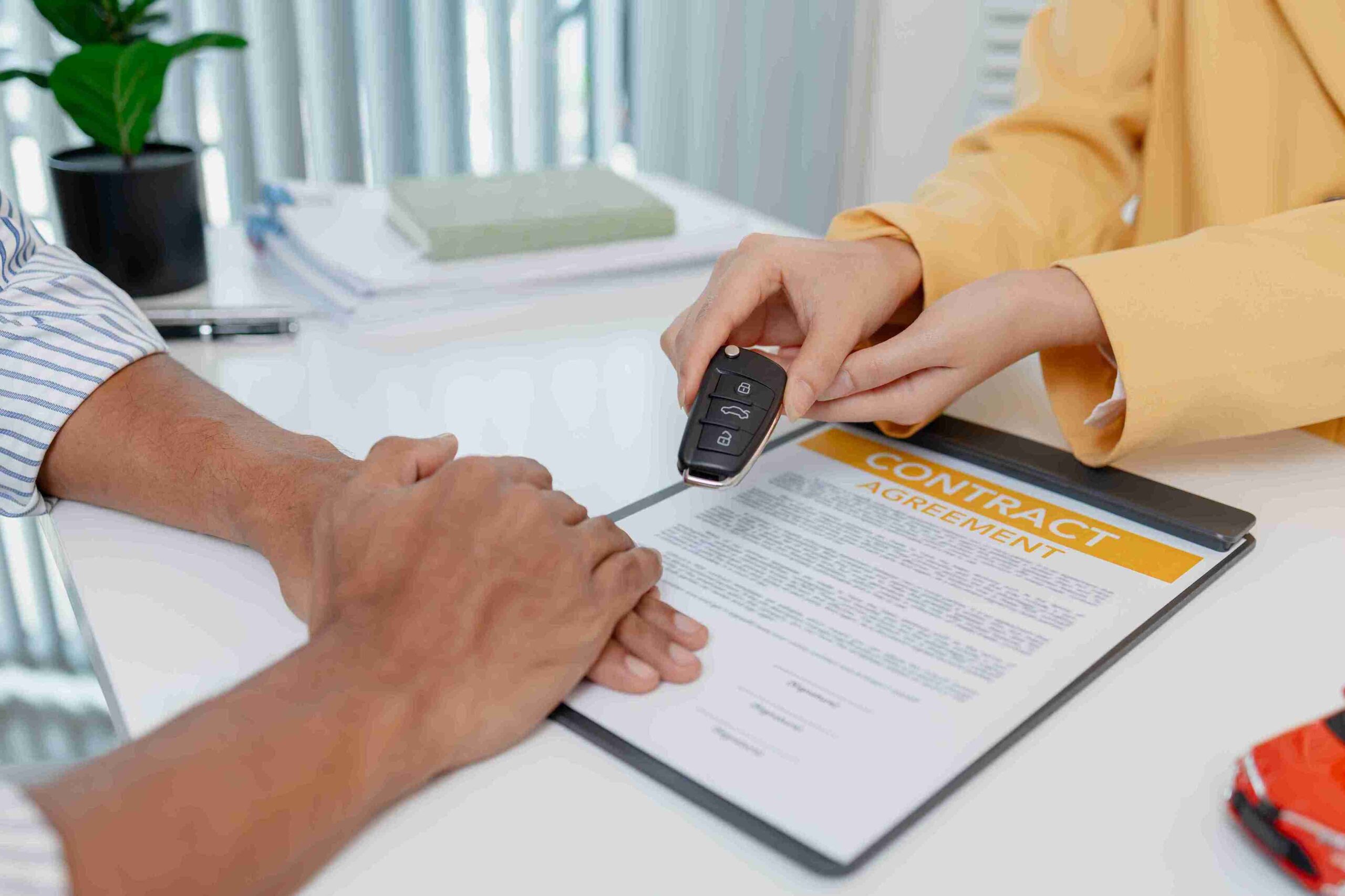 A man holds a car key while a woman's hand reaches out, suggesting a moment of sharing or decision-making.