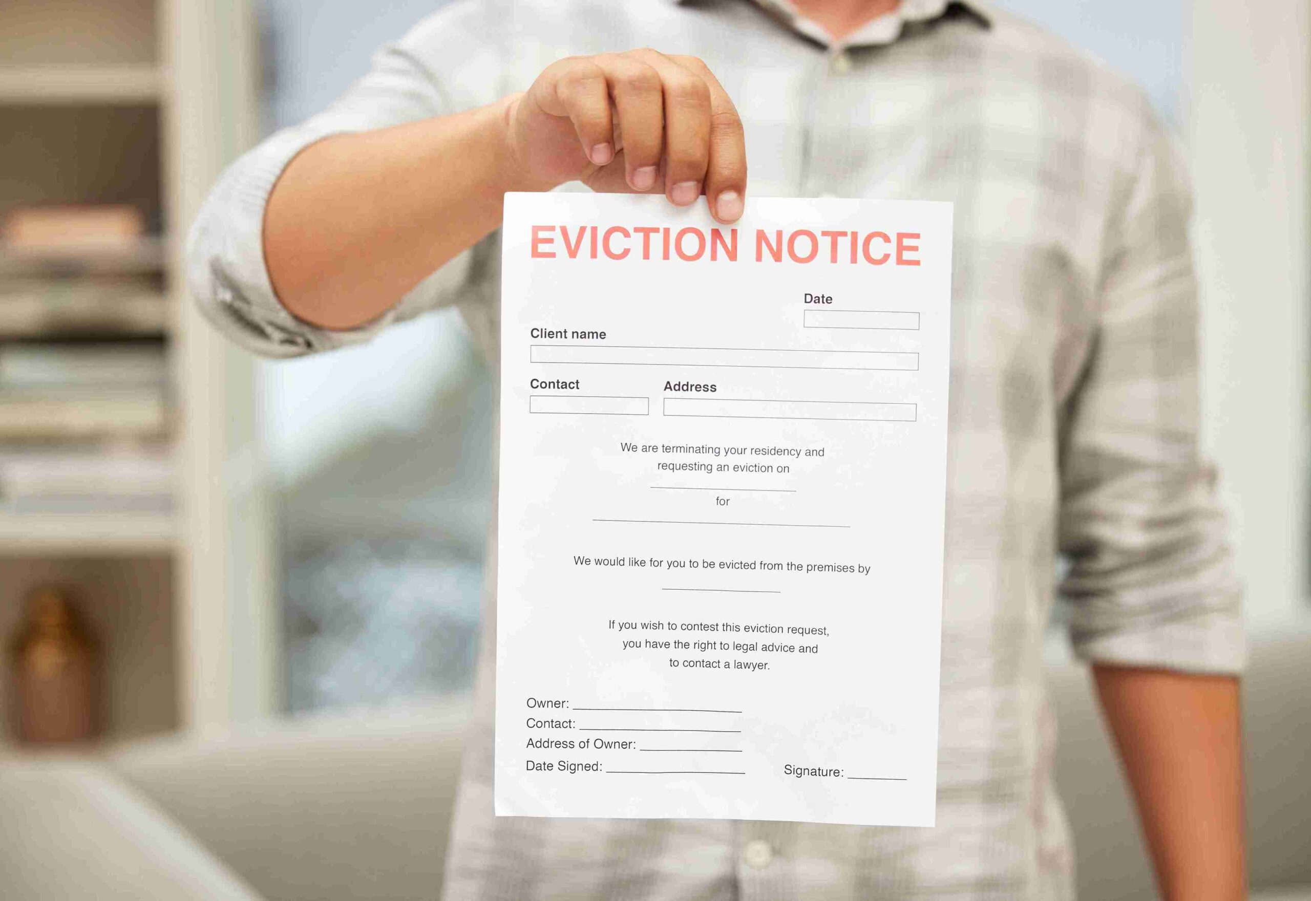 A man holds an eviction notice, displaying concern and uncertainty about his housing situation.