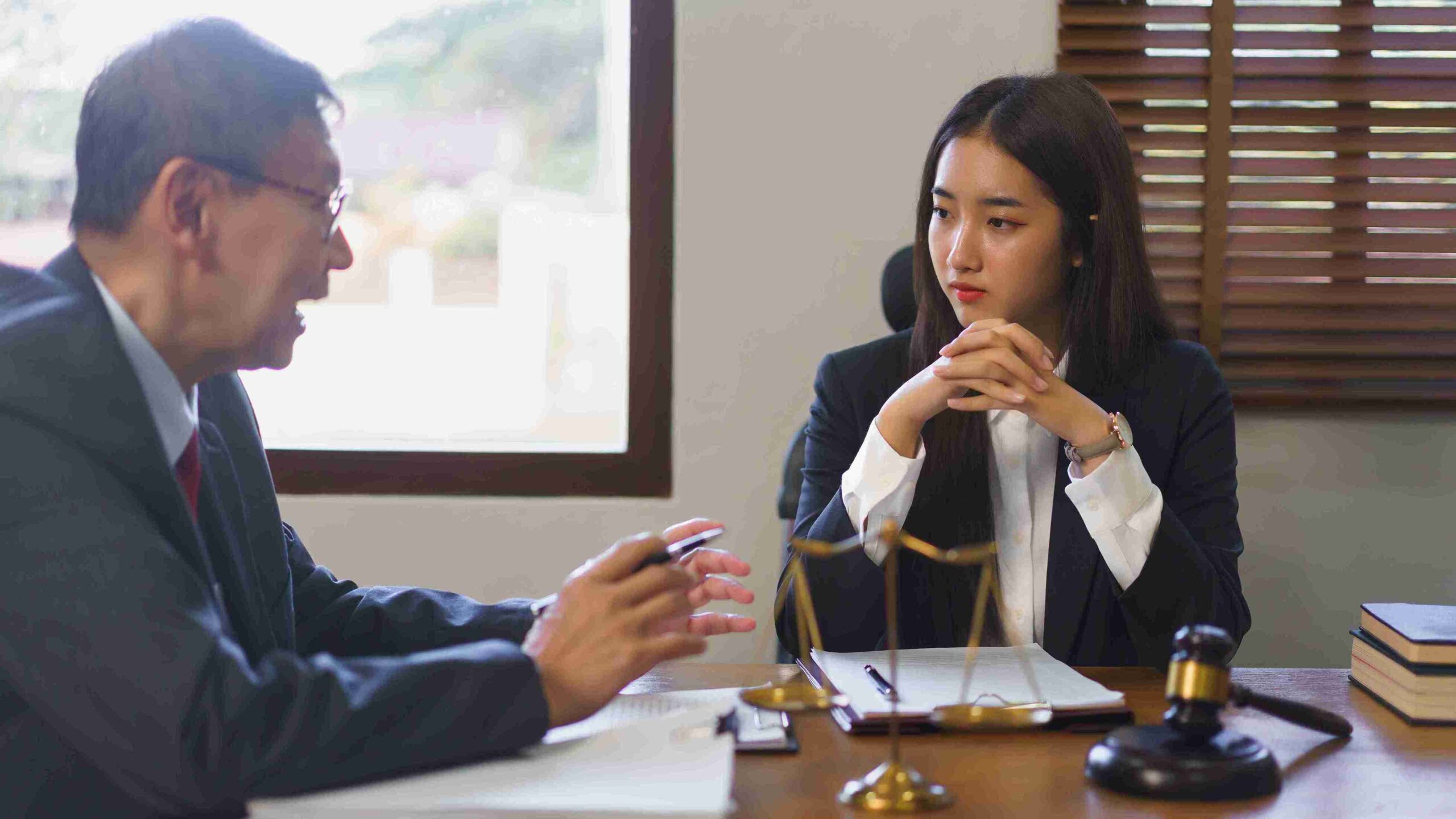 A man and woman in business attire collaborate at a desk, focused on their work and discussing ideas.