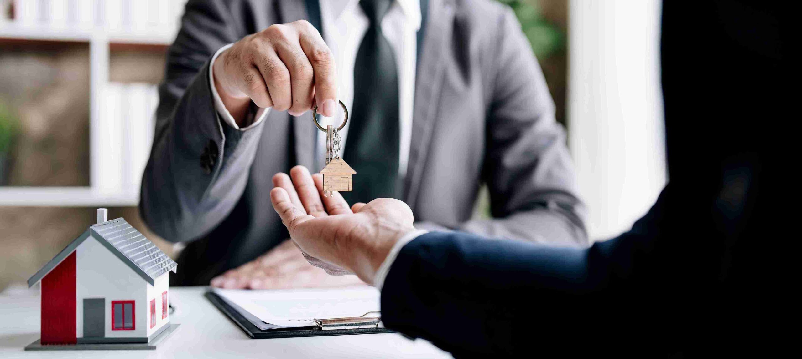 A man hands a key to another man, symbolizing a transfer of responsibility or access.