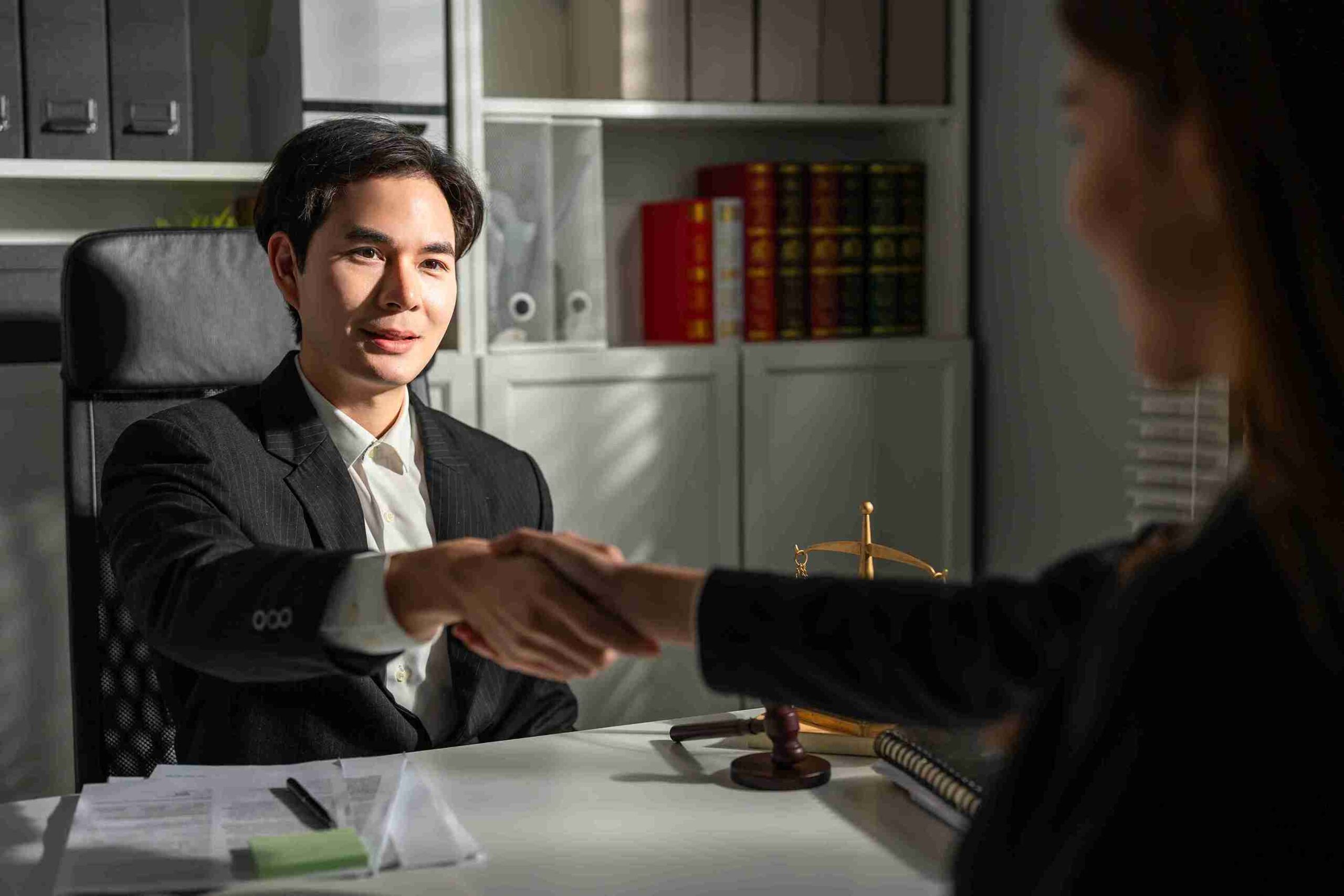 Man and unknown genders handshake in office.